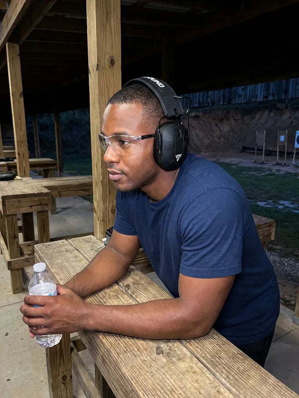 A shooter leans on the bench at dusk, still wearing the VX1 PRO after a long range day