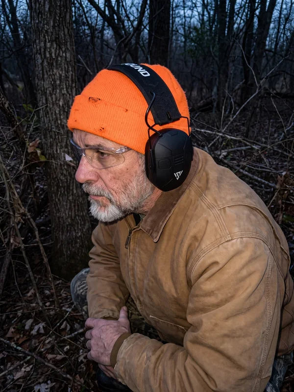 A hunter in a brush blind at dusk wearing the VX1 PRO over safety glasses